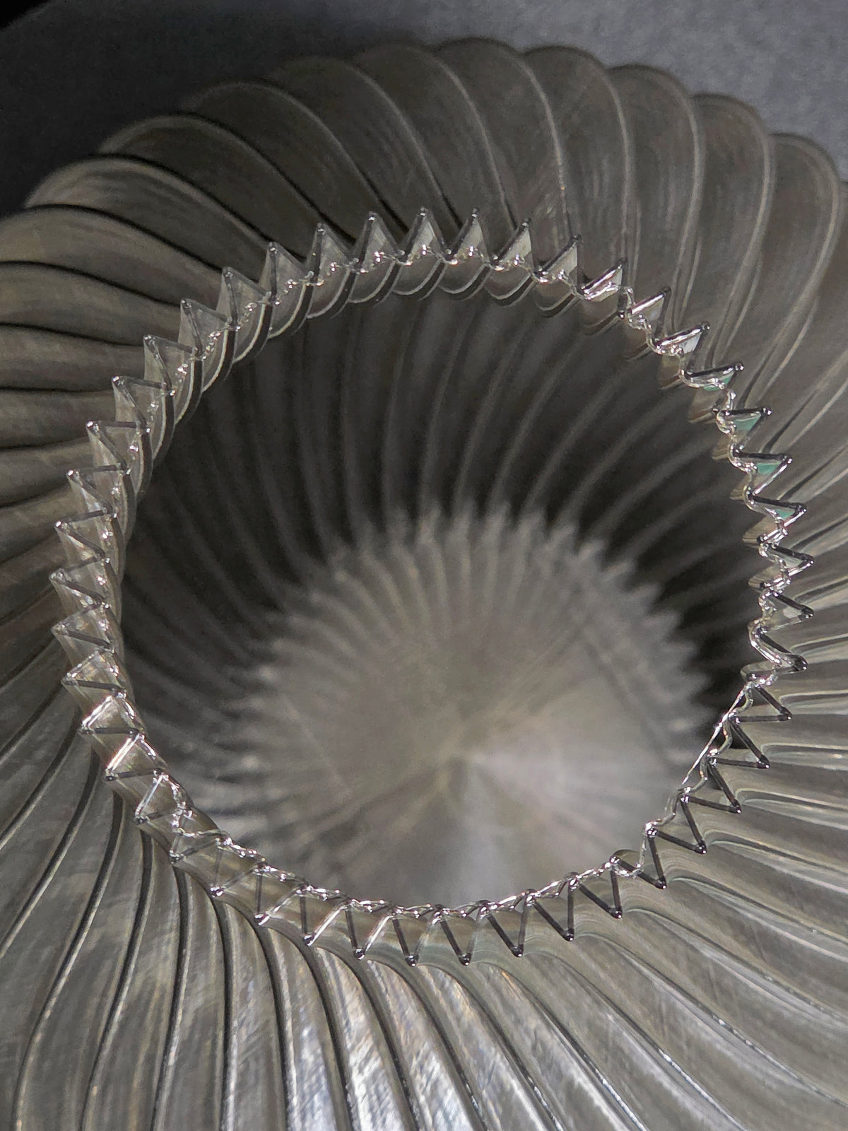 Close-up of the interior of a translucent gray, ribbed vase with a textured surface.