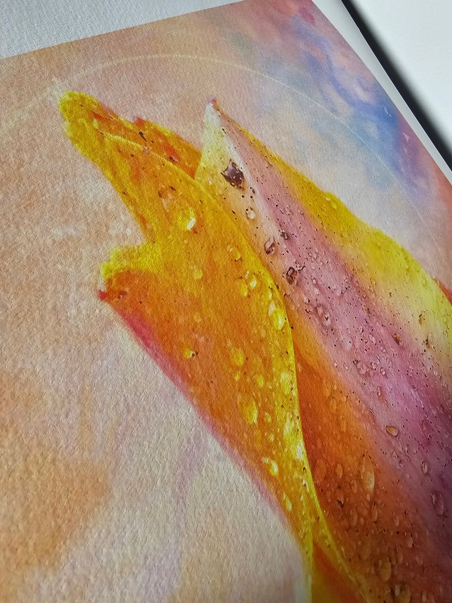 Close-up of a watercolor painting with yellow and pink strokes on textured paper.