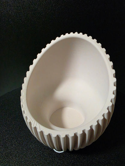 A white plastic or resin bowl-shaped component with a fluted outer edge, photographed from above on a black textured background.