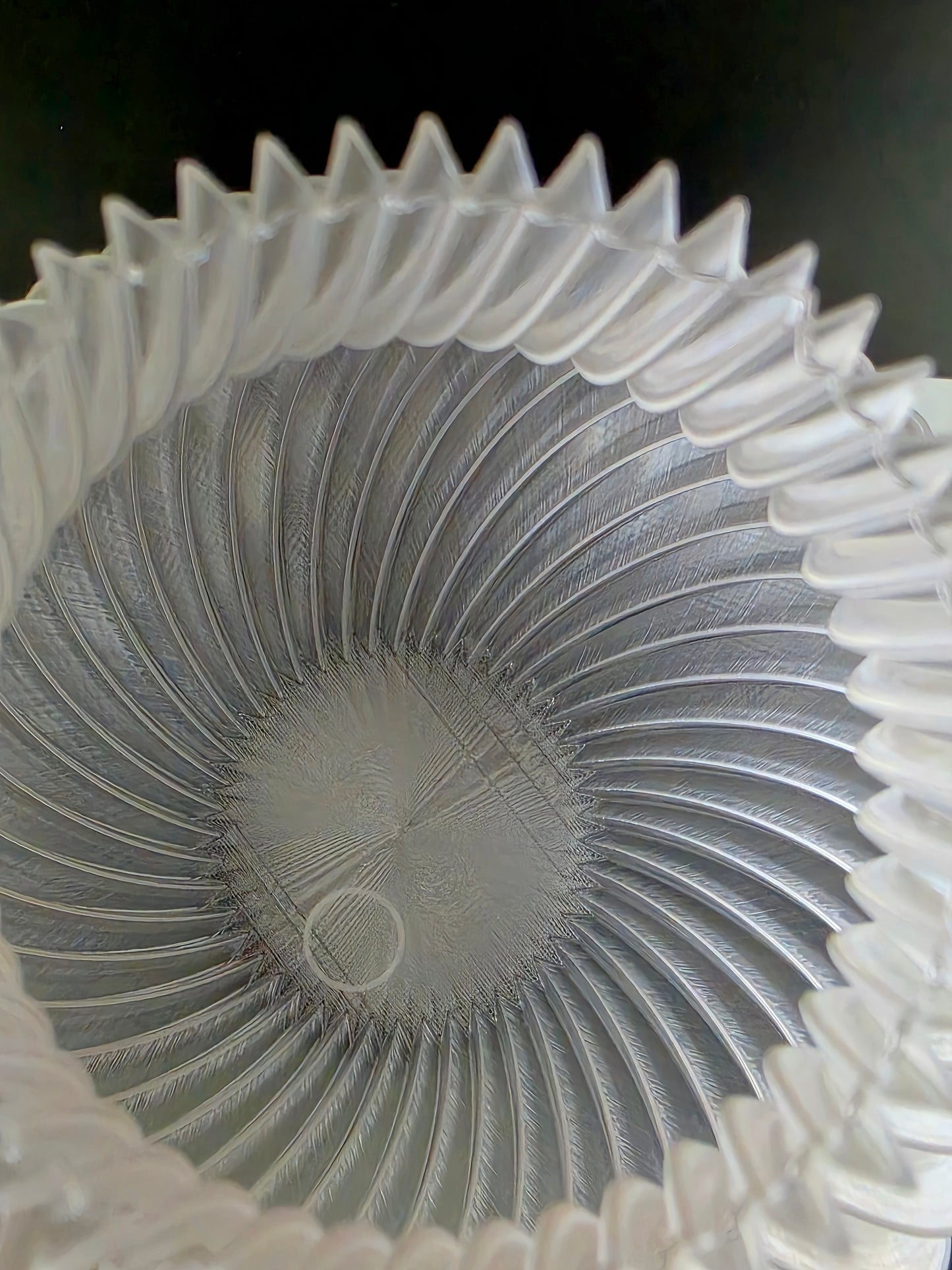 Close-up of the inside of a transparent vase with a ribbed design on a black background