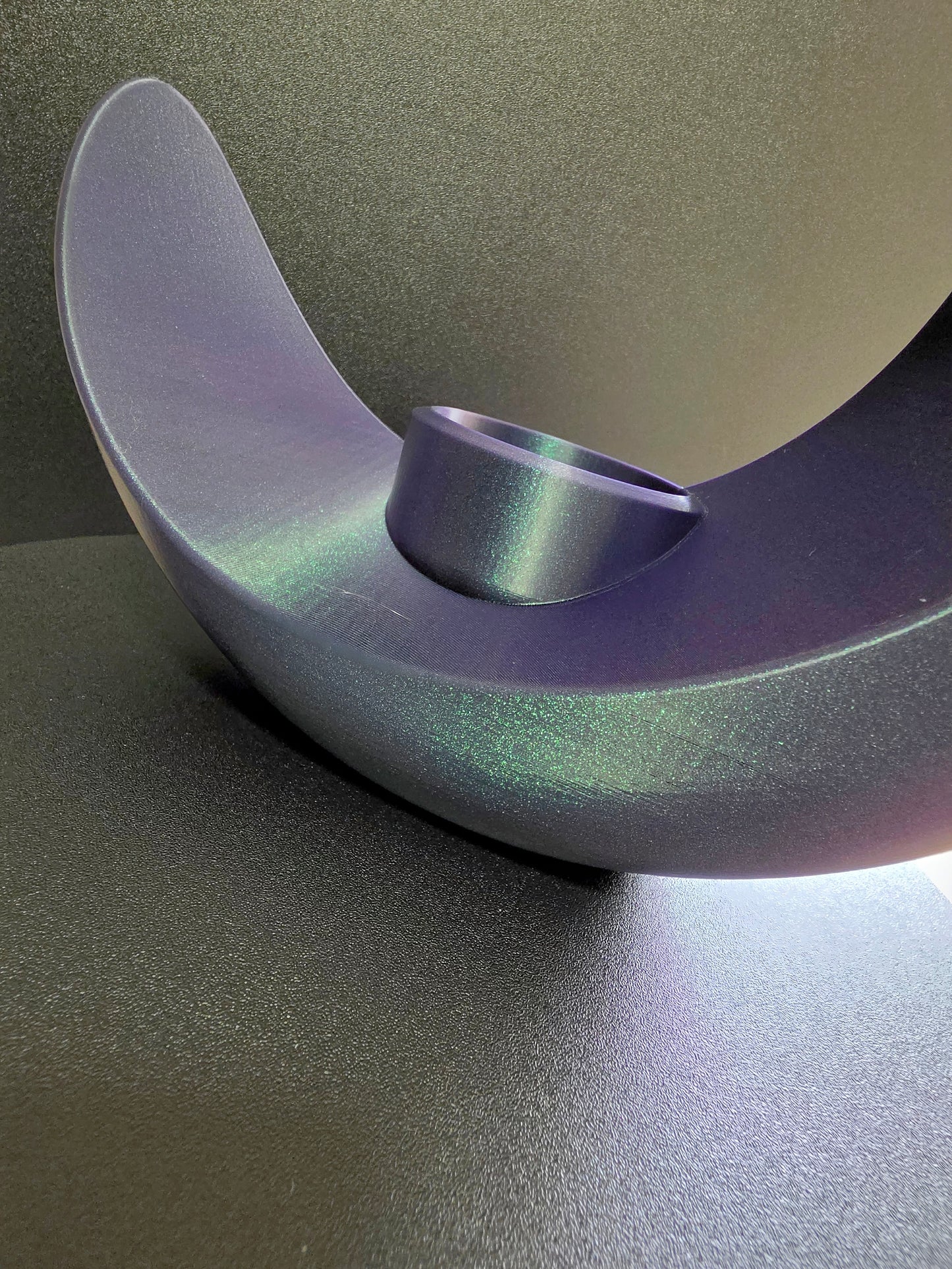 Metallic purple object on a reflective surface with a gradient background