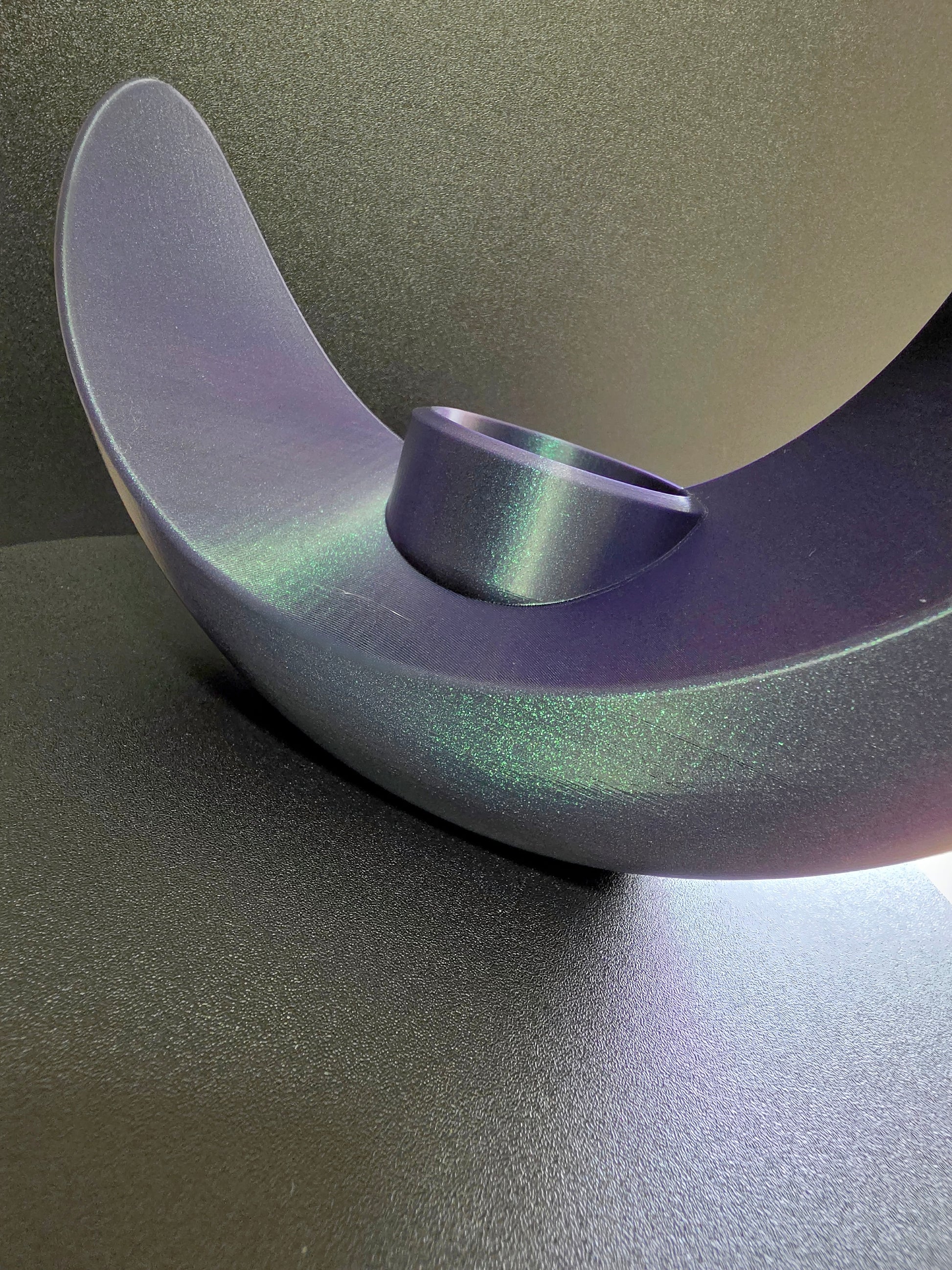Metallic purple object on a reflective surface with a gradient background