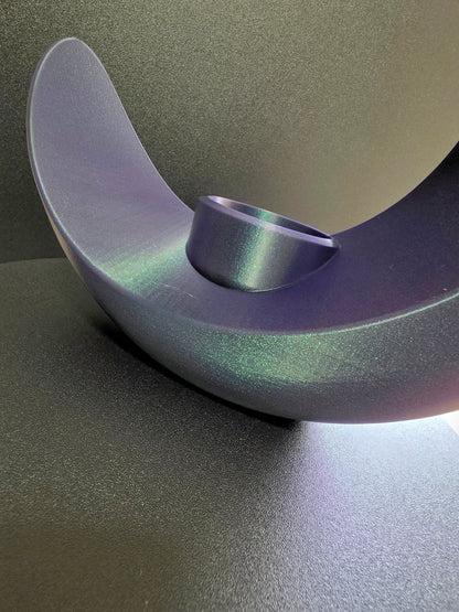 Metallic purple object on a reflective surface with a gradient background