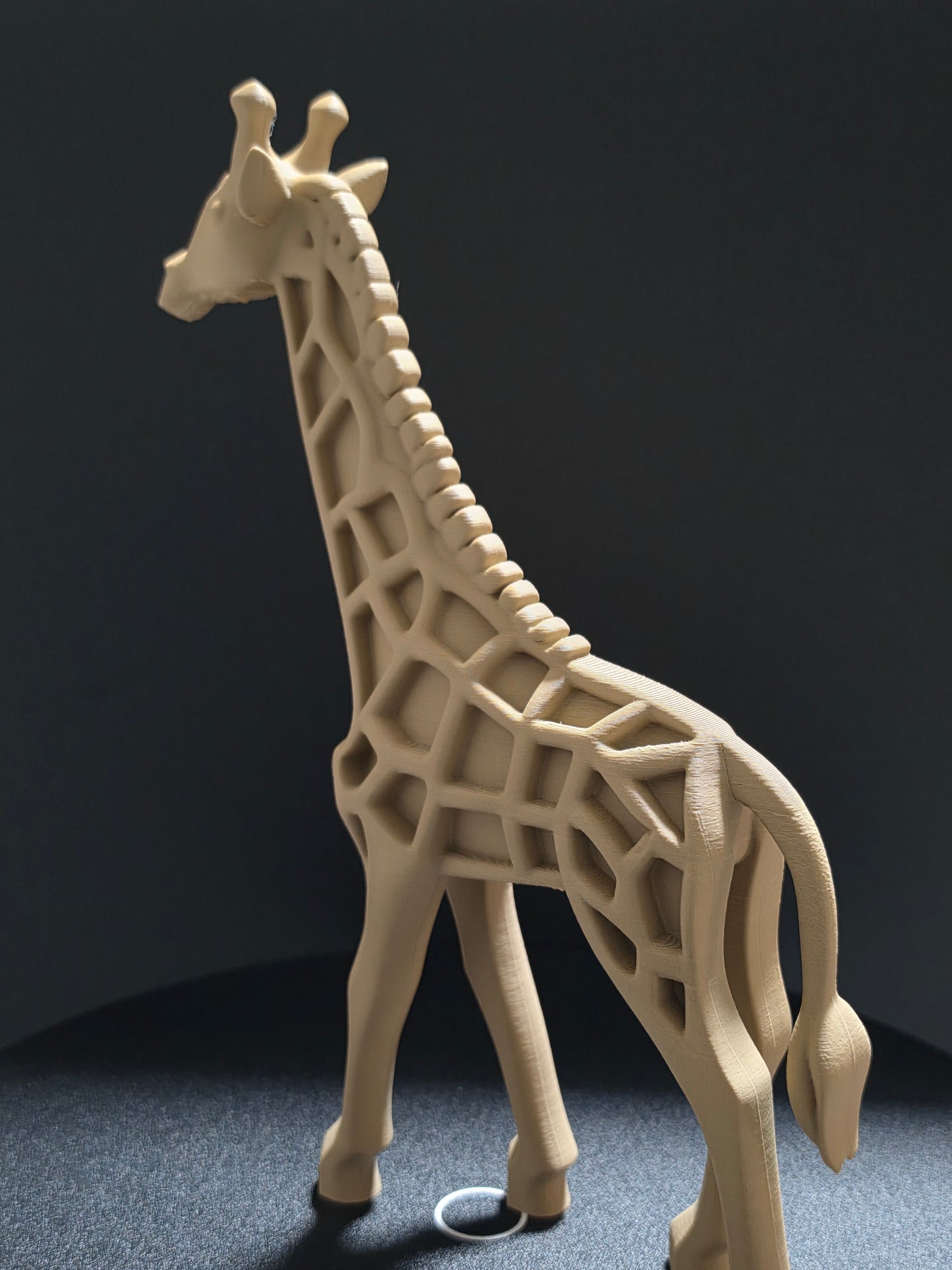 3D-printed giraffe model on a dark surface