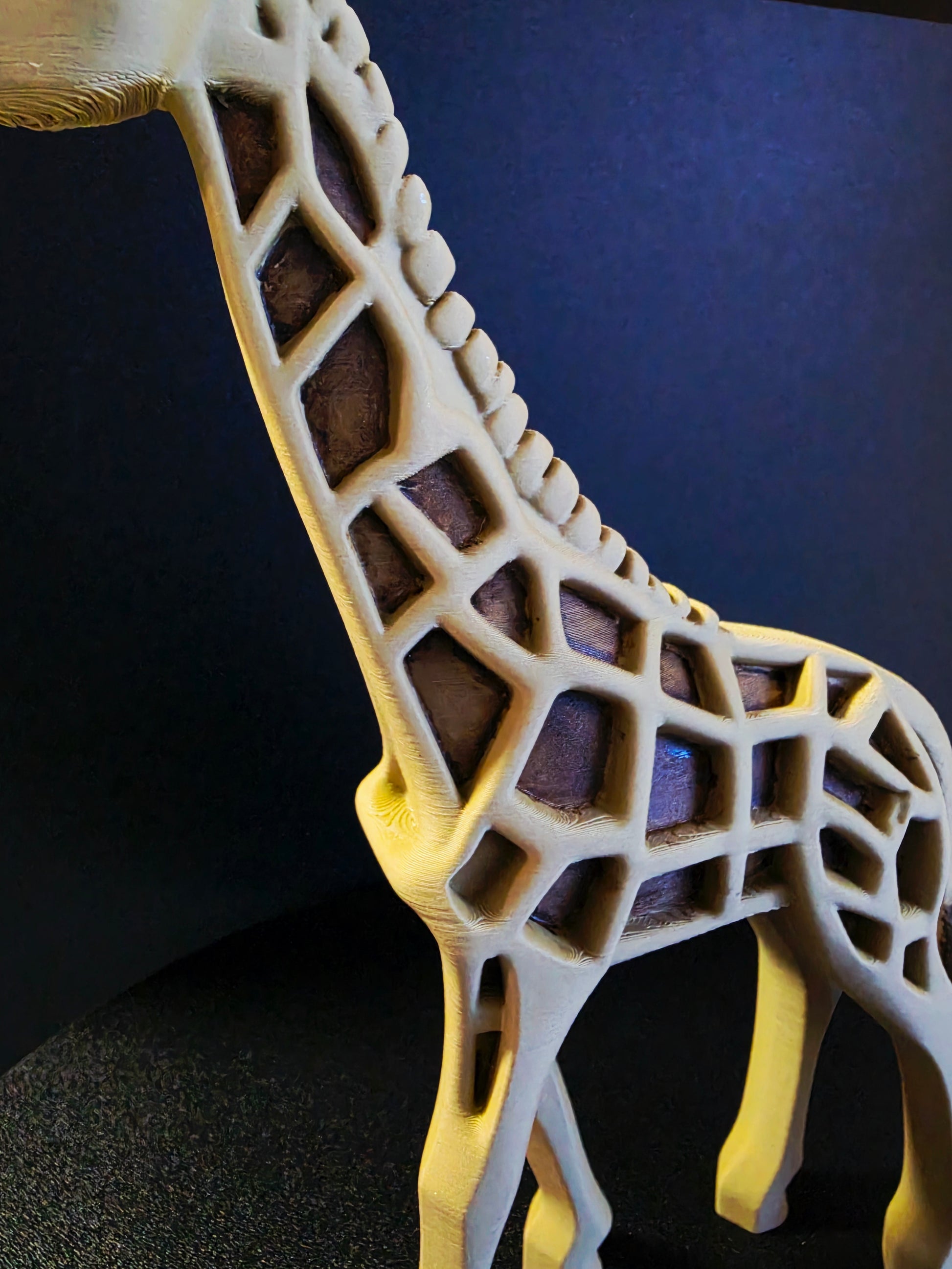 3D-printed giraffe model with a geometric design on a dark background