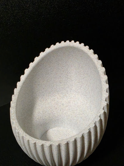 A white speckled ceramic bowl with a fluted, ribbed exterior and a scalloped rim, shown against a solid black background.