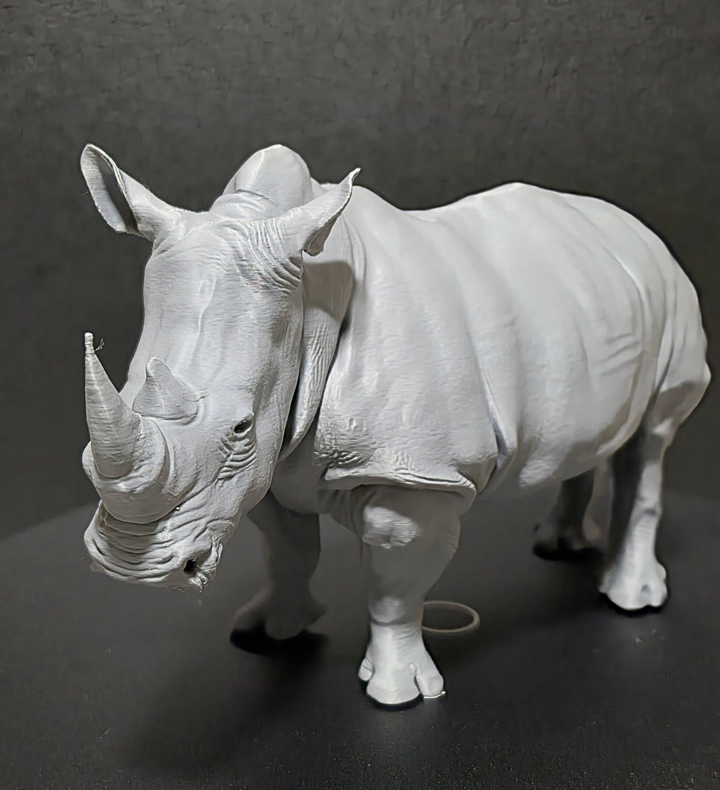 Gray rhinoceros figurine on a dark gray background