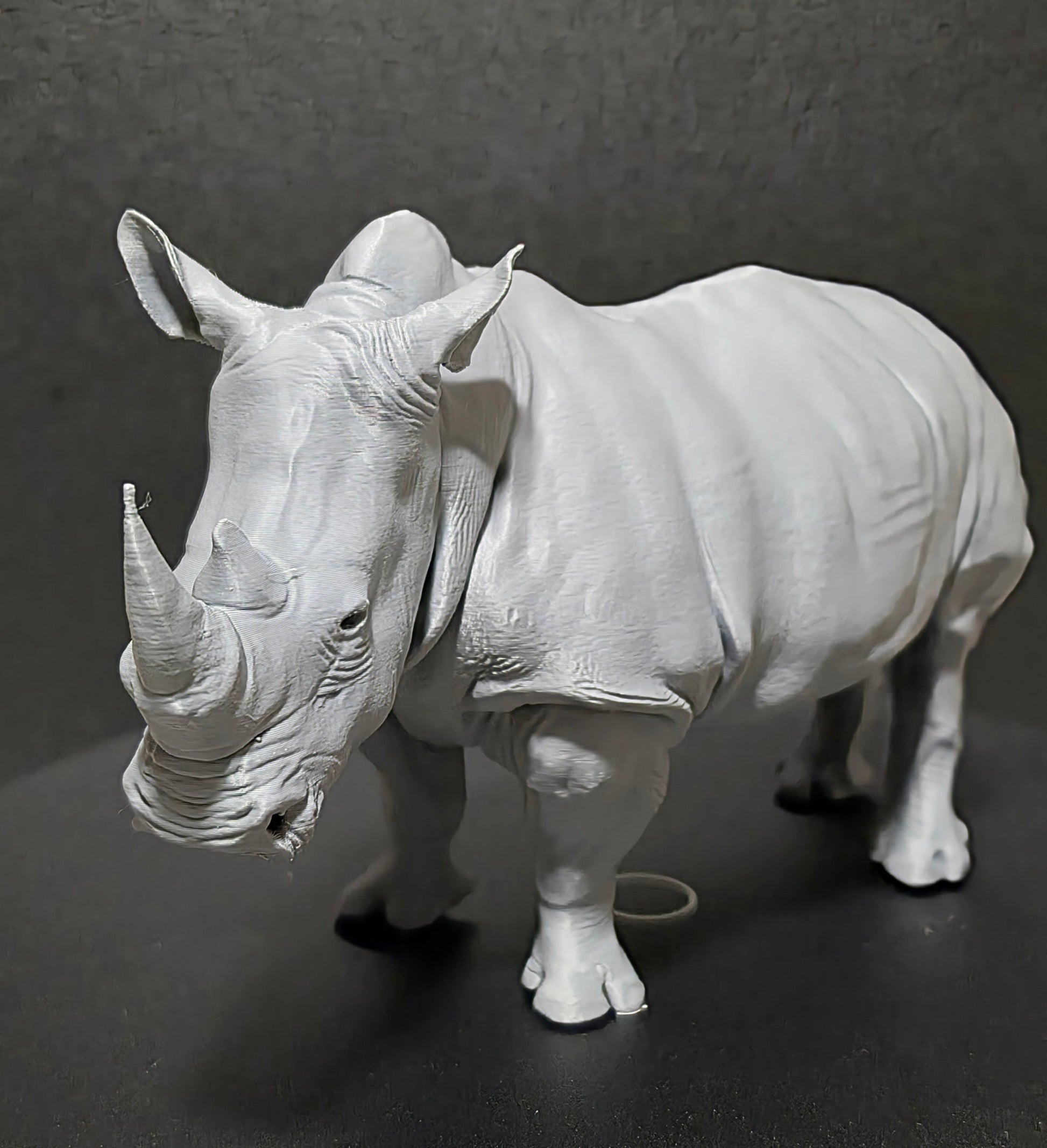 Gray rhinoceros figurine on a dark gray background