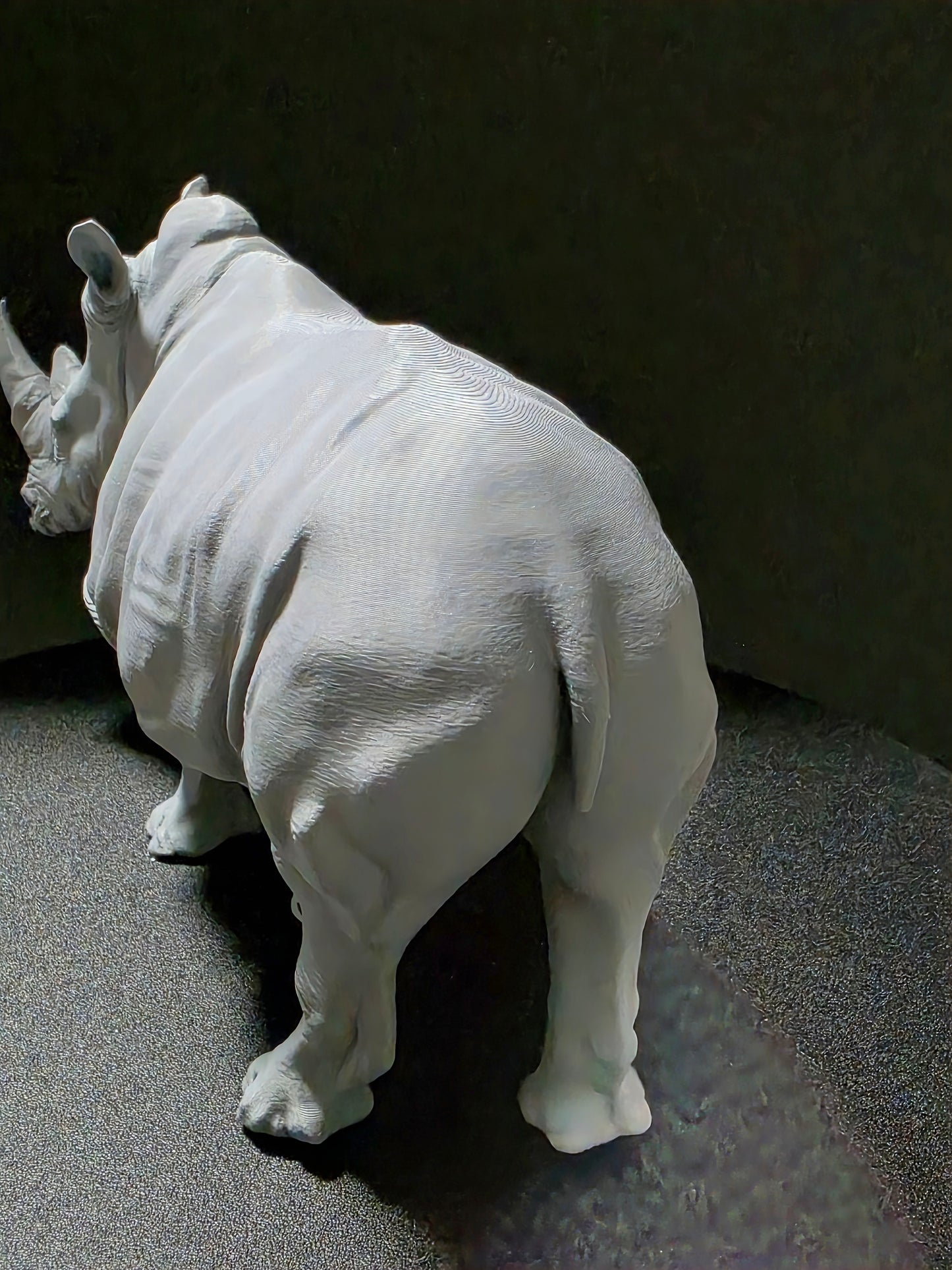 White rhinoceros sculpture on a dark gray surface