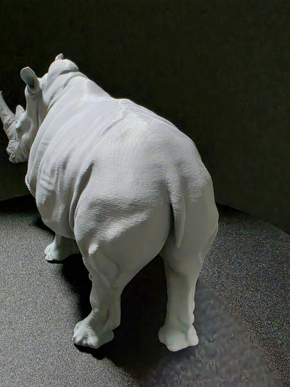 White rhinoceros sculpture on a dark gray surface