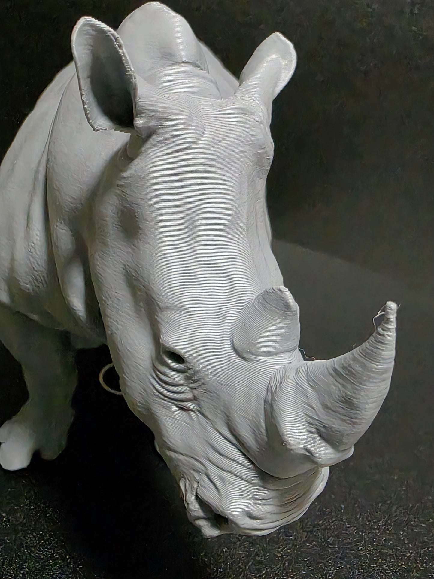 White ceramic sculpture of a rhinoceros head on a dark background