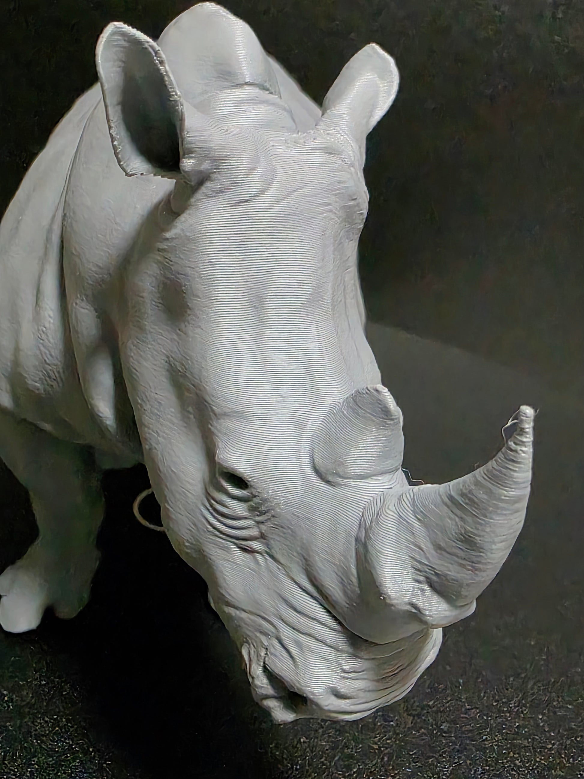White ceramic sculpture of a rhinoceros head on a dark background