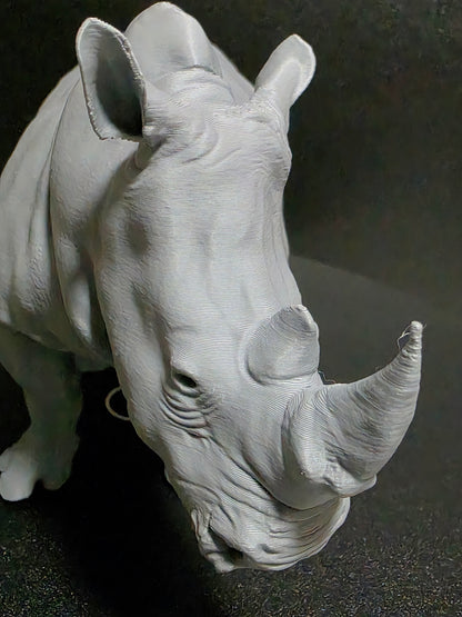 White ceramic sculpture of a rhinoceros head on a dark background