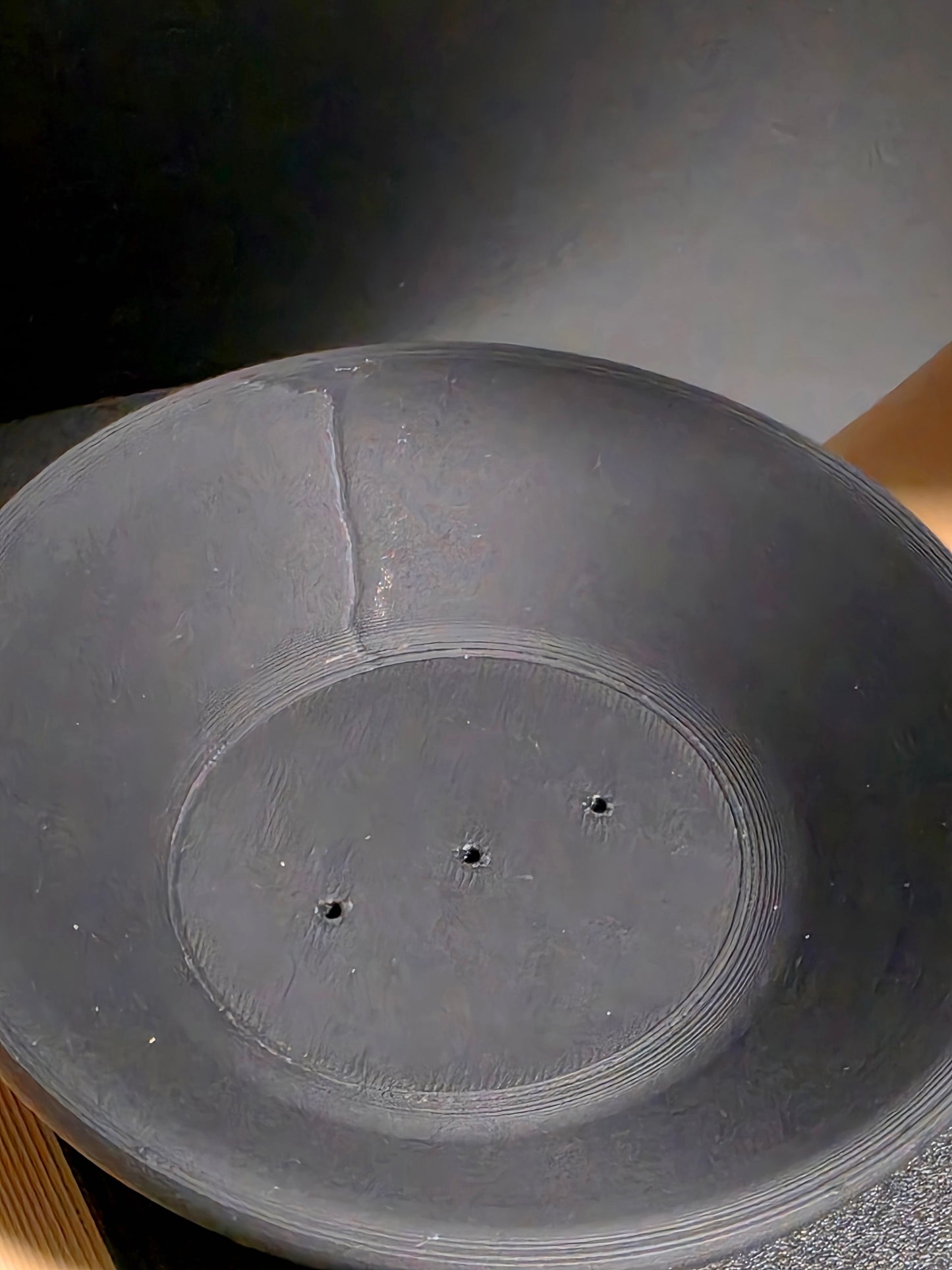 Close-up of a black tea candle with incense holes on a gray background