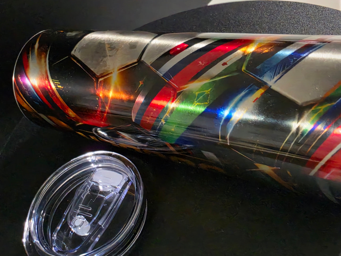 Multicolored tumbler with a clear lid on a dark surface