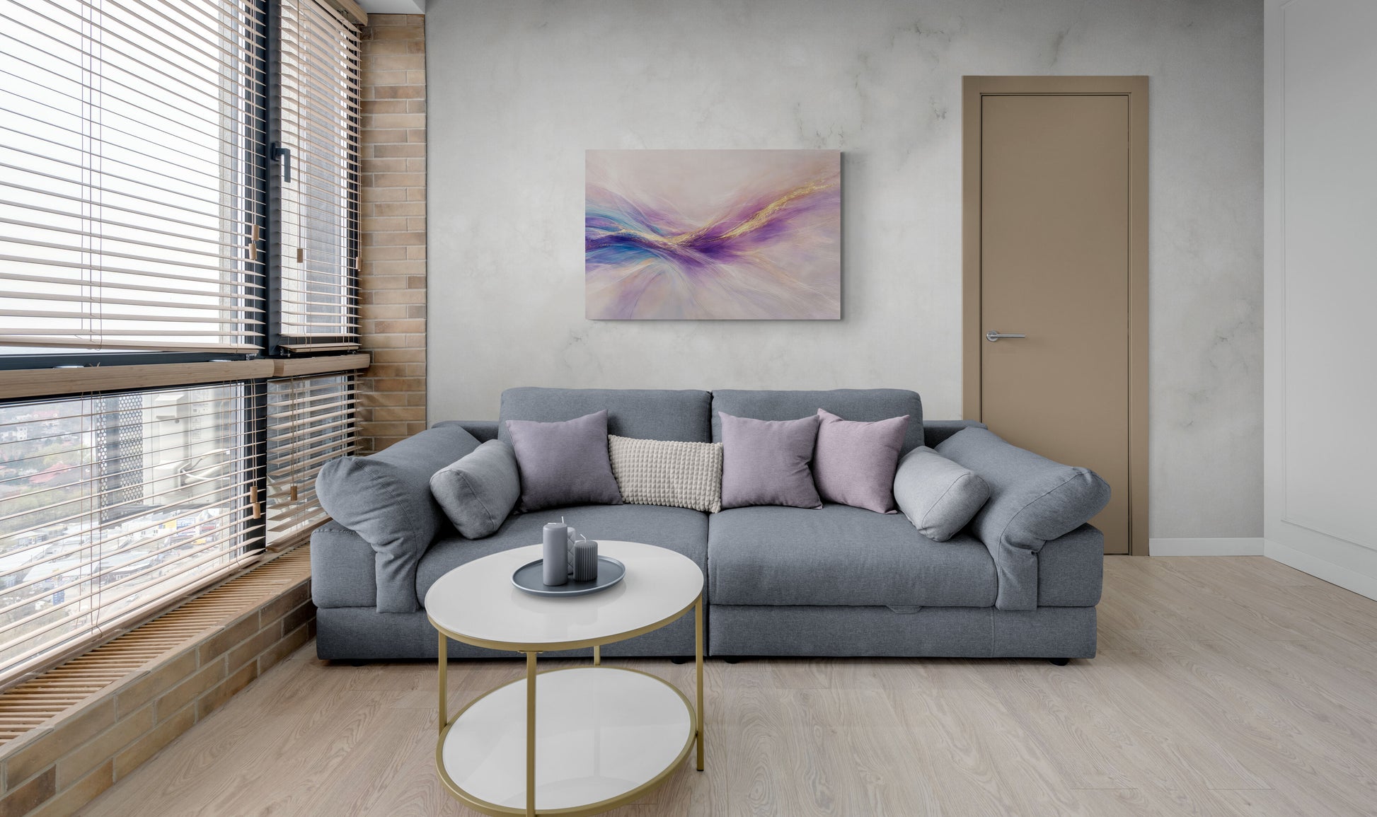 Modern living room with a gray sectional sofa, round coffee table, and abstract painting on the wall.