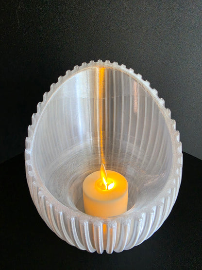 Clear tealight holder with a yellow light inside on a black background