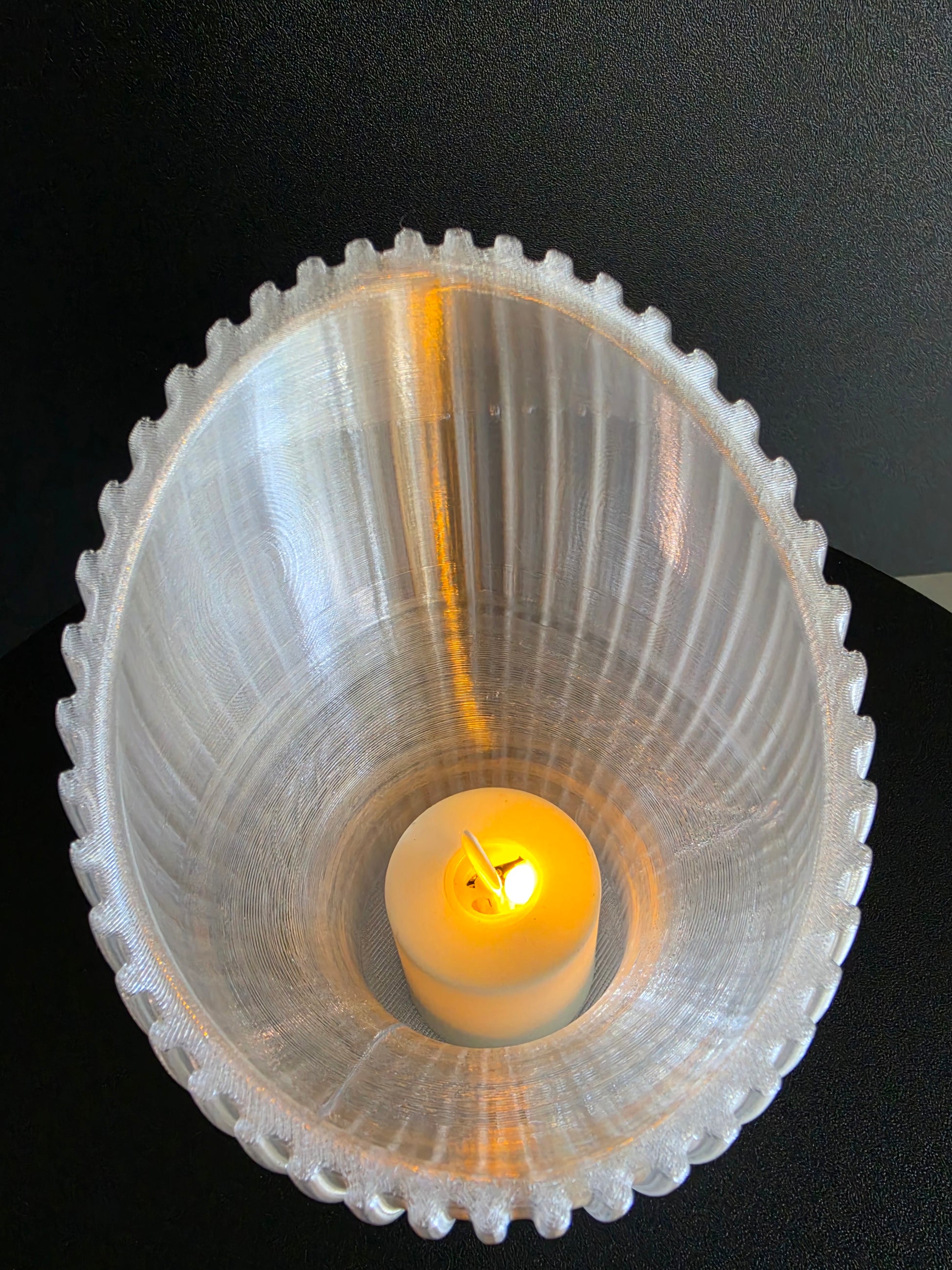 Decorative tealight holder with a candle on a black background