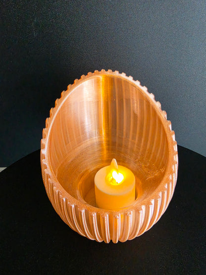 Cylindrical  candle holder with a lit candle inside on a dark background