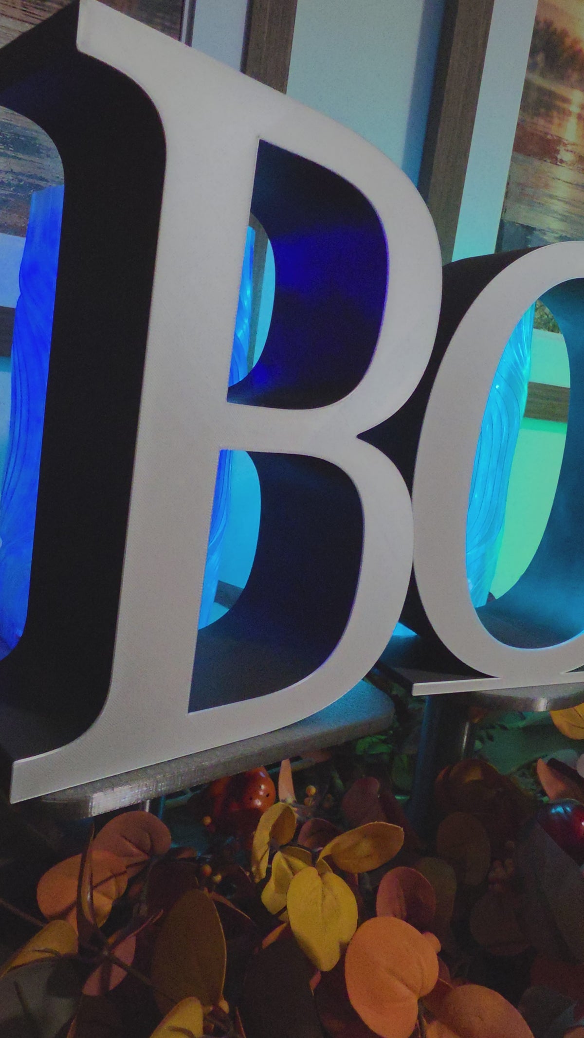 Large 9 inch letters that spell BOO placed on a console with fall decor. The video pans horizontally over each letter that is black with a white front layer.