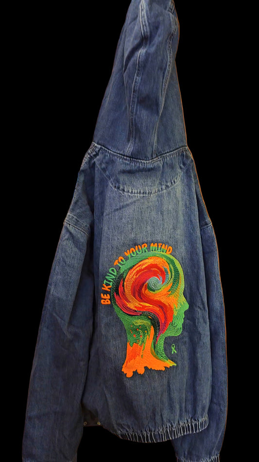 Blue denim jacket with a colorful graphic design on a wooden surface