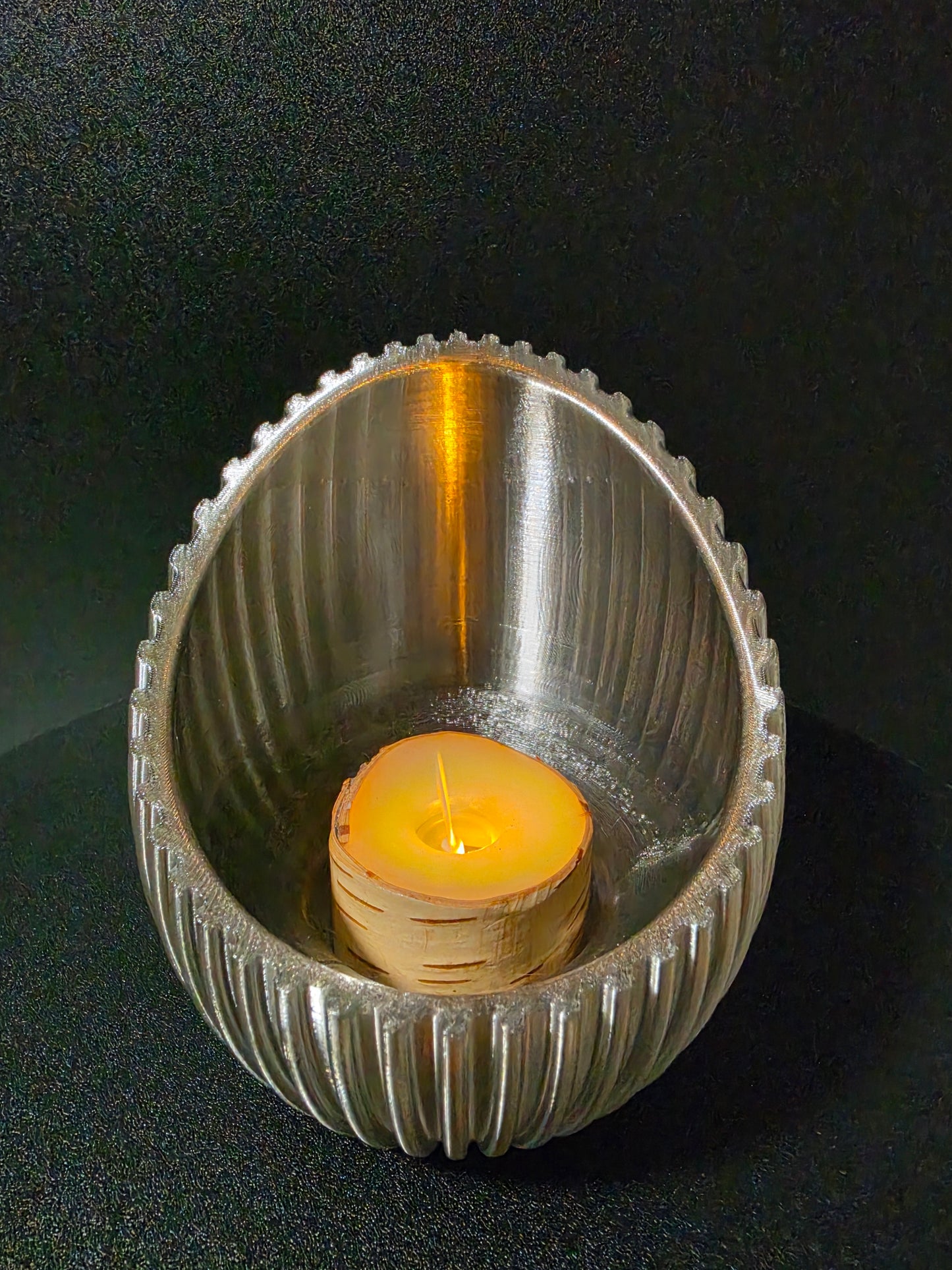 black candle holder with a lit candle on a dark background